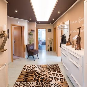 Heller Flur mit afrikanischen Dekorationen, Tierfell-Teppich und moderner Einrichtung.