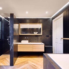 Modernes Badezimmer mit dunklen Fliesen, ebenerdiger Dusche und Holzwaschtisch.