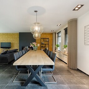 Modernes Esszimmer mit großem Holztisch, schwarzen Stühlen und stilvoller Einrichtung.